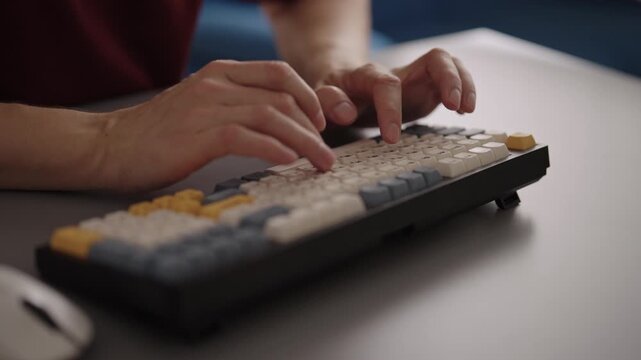 Close-up of persons hands typing on custom mechanical keyboard with colorful keys sitting at office desk. Concepts of programming, writing, office work, digital communication. Shooting in slow motion.