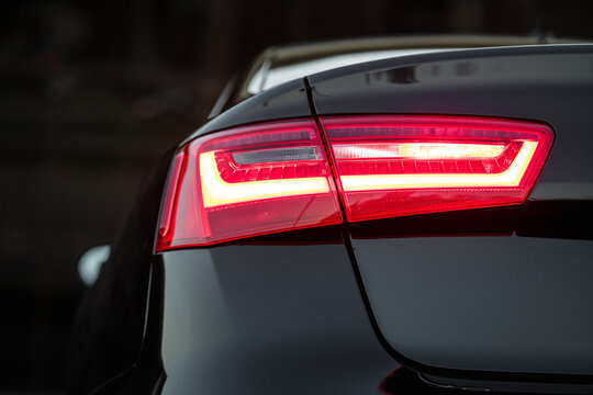 Rear taillight of black luxury sedan at dusk