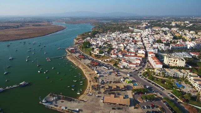 Beautiful aerial view showing the charming coastal town of alvor with its white houses and the bustling harbor filled with boats, located in the scenic algarve region of southern portugal