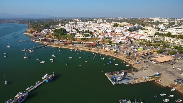 Stunning aerial view showcasing the picturesque fishing village of alvor with its charming white houses, bustling harbor with many boats, and serene coastal landscape in algarve, portugal
