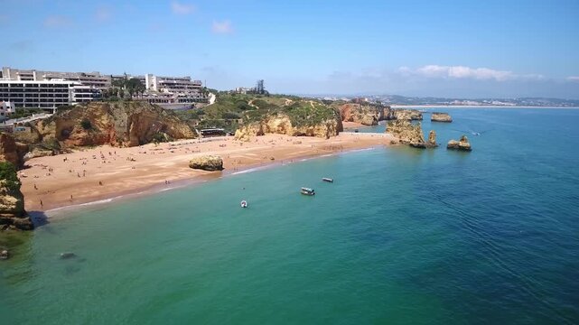 Stunning aerial perspective of praia dona ana beach in lagos, portugal, showcasing its famous golden cliffs, rock formations, and clear turquoise water on a beautiful sunny summer day