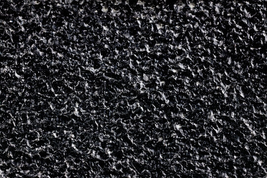 Painted cast metal surface texture. Rough black iron material with glossy dark industrial coating. Close up background of metallic bumpy structure for backdrop, element, heavy industry pattern.
