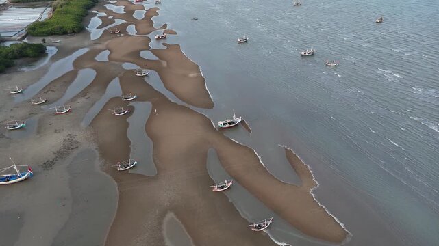 Aerial drone view of fishing boats beached on mudflats during low tide in coastal estuary