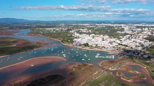 Beautiful aerial perspective of the charming fishing village of alvor, showcasing its historic whitewashed buildings, marina filled with sailboats, and the serene ribeira de odiaxere