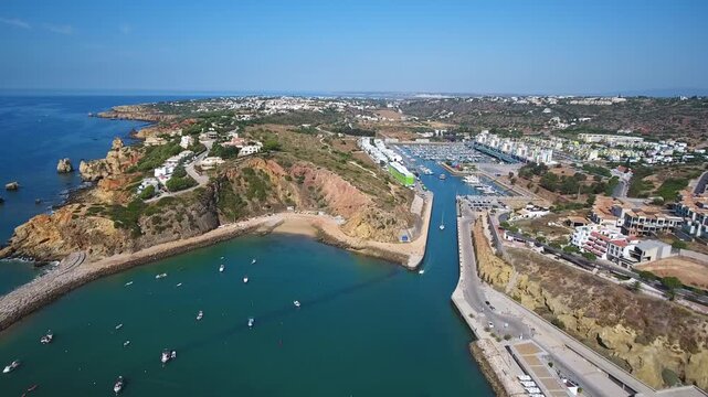 Aerial approach over albufeira marina revealing rocky algarve coastline, azure sea, yachts and sunlit waterfront town  a scenic southern portugal travel and seaside destination