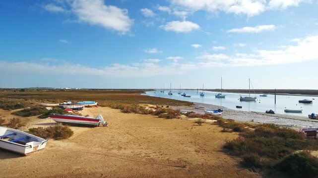 Beautiful aerial footage showing fishing boats moored on the riverbank and anchored in the water at low tide in santa luzia, algarve, a popular tourist destination in southern portugal