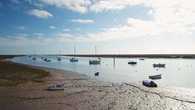 Rising tide lifting boats moored in a tranquil estuary in santa luzia, algarve, portugal, with some vessels stranded on the mudflats during low tide now floating on the incoming water