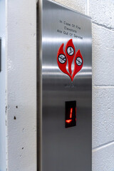 Vertical photo of an elevator with a safety notice stating “In case of fire elevator will be out of service,” emphasizing fire safety © Juli