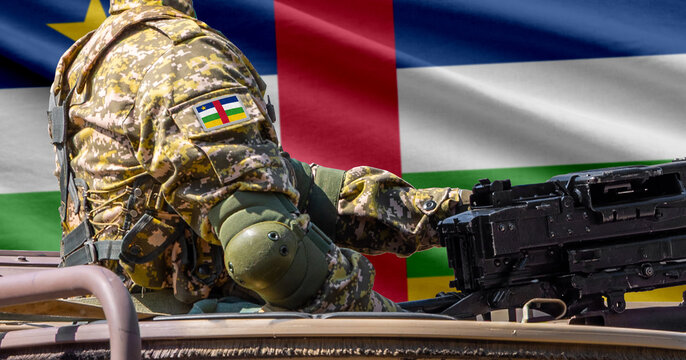 Central African Republic flag with soldier at machine gun turret in front of it. Closeup side view.