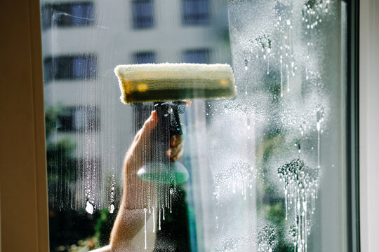 Microfiber washer spreads soapy water on window glass. Window washing technique, how to clean windows, cleaning guide, tutorial