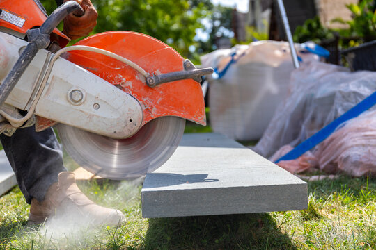 closeup of construction worker cutting bluestone with a gas powered masonry circular saw