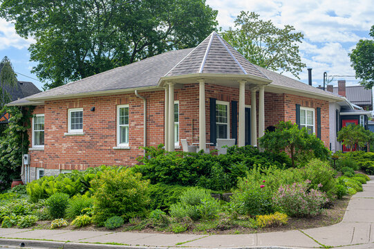 Single-story brick house with wraparound porch and landscaped corner garden.