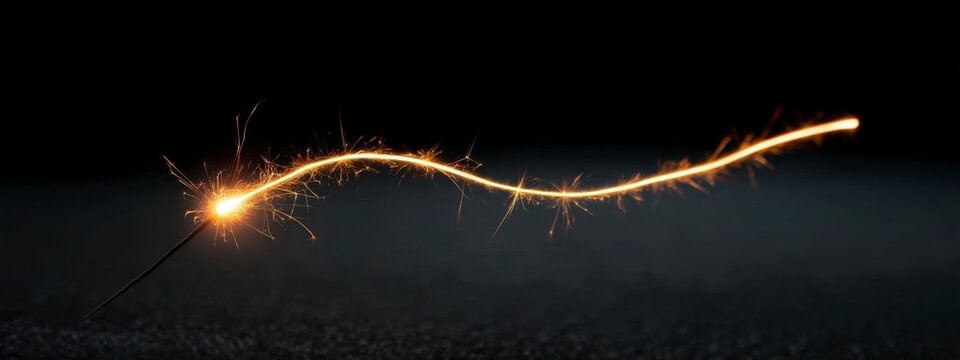 Sparkler burning with a glowing trail on a dark background