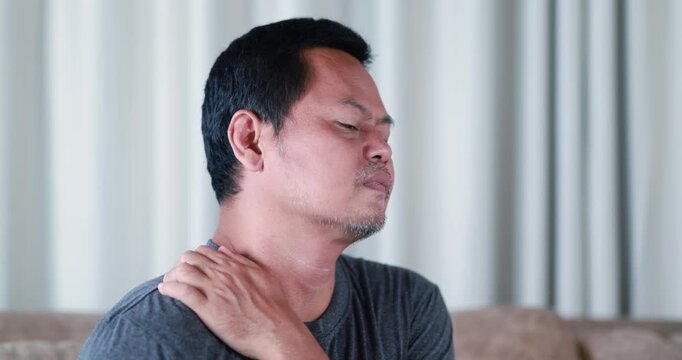 Adult man massaging his neck to relieve neck and shoulder pain, shoulder and upper back pain, muscle stiffness, office syndrome, fatigue, poor posture, self massage, pain relief, healthcare concept