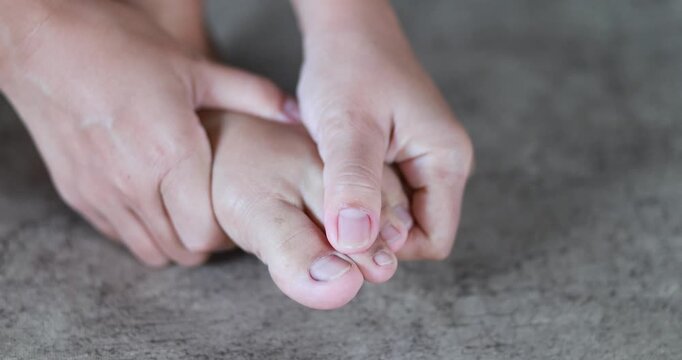 Massaging the foot and toes, hands holding a painful toe, foot massage, foot pain, toe injury, inflammation, muscle strain, podiatry, medical treatment, foot care, and healthcare