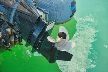 Boat outboard motor propeller close‑up over green water © Leonid
