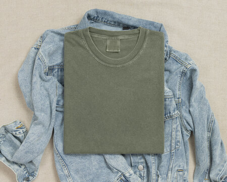 Blank washed green folded shirt mockup over blue denim jacket, crewneck template for print on demand