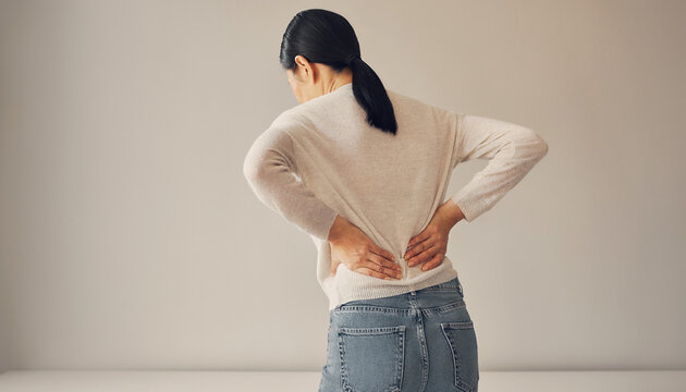 腰に手を当てて腰痛を訴える女性の後ろ姿