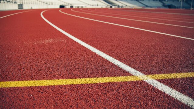 Red running track with white lane markings at a stadium. Sports concept for competition or athlete training background.