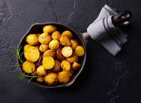 Roasted baby potatoes flatlay on dark stone background with copy space. Top view.