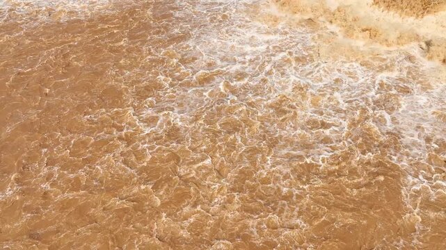 Aerial perspective captures violent muddy flood currents after heavy rainfall, highlighting global warming, extreme precipitation, rain bomb events, runoff and severe flooding.
