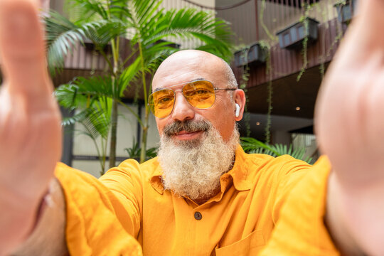Smiling bearded man take selfie in tropical courtyard