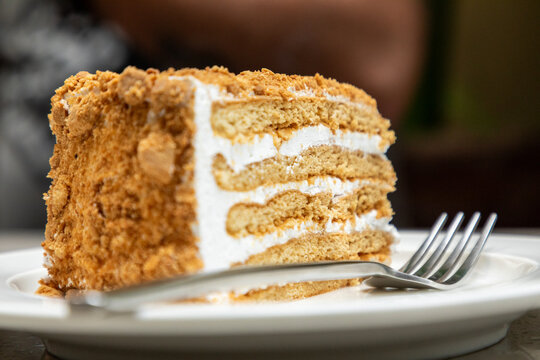 Layered honey cake slice with cream and crumb topping