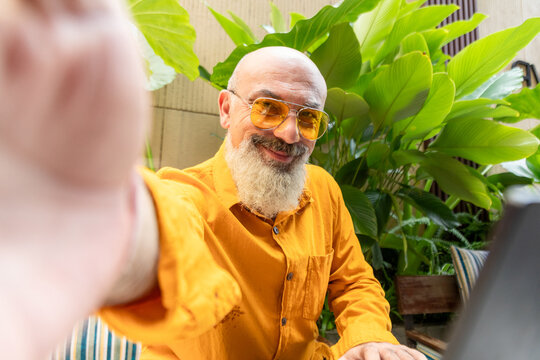 Smiling bearded man take selfie beside tropical plant