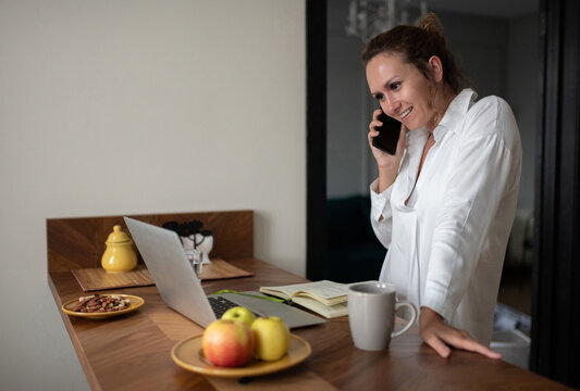 Cheerful businesswoman answering phone call at home