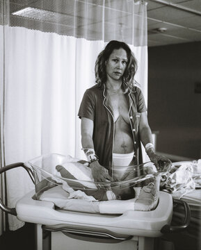 A woman stands with her newborn baby after giving birth.