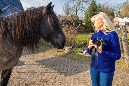 Woman photographer with horse in rural village setting