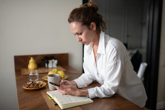 Female entrepreneur checking smartphone at home