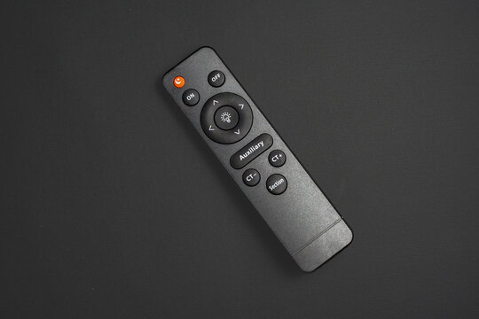 High angle view of a sleek black remote control on dark background, minimalist tech product photography.