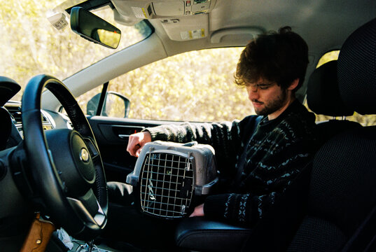 Man sits in car with cat in pet carrier