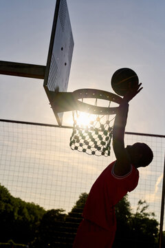 Basketball Player Makes a Slam Dunk at Sunset on the Court