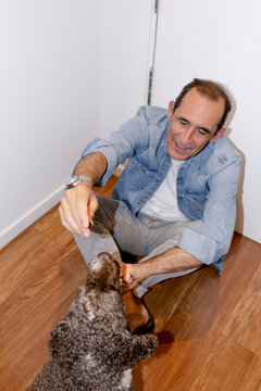Older man rewarding his dog during indoor training session