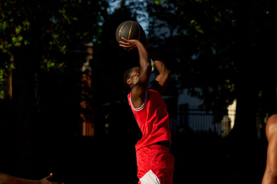 Basketball Player Takes a Shot at Outdoor Court During Daylight