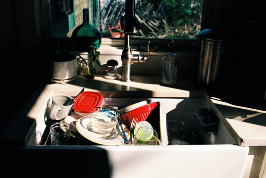 Morning sun on sink filled with dirty dishes