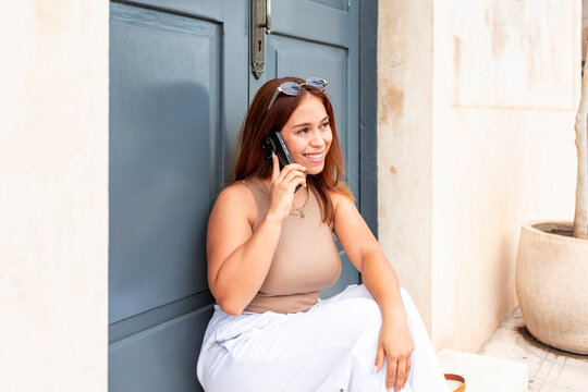 Smiling woman talk on smartphone by blue doorway