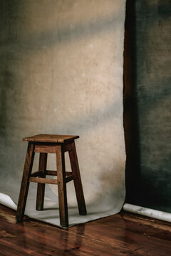 Wooden Stool Next to Backdrop in a Studio Setting