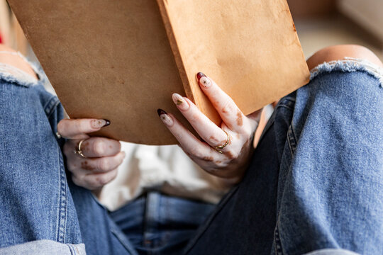 Woman with vitiligo hands holding books in denim jeans