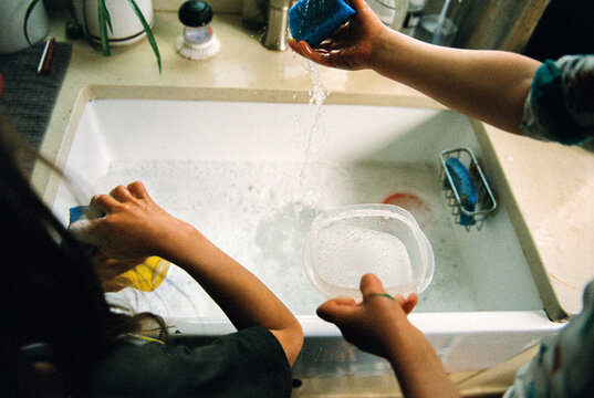 Detail of kids playing with water in the kitchen sink