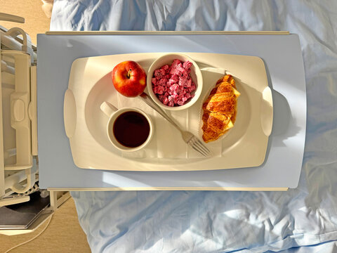 Hospital breakfast tray with coffee, apple and croissant