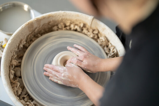 Potter shaping clay on spinning pottery wheel