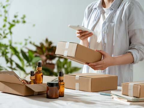 Small business owner scanning package with smartphone for shipping