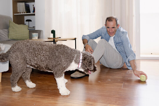 Senior man playing fetch with his dog at home