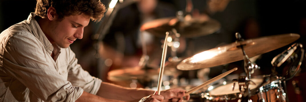 Schlagzeuger spielt an Drumset mit Becken, warmes B&uuml;hnenlicht in Orange