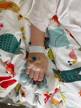 Child hand with intravenous cannula in hospital bed