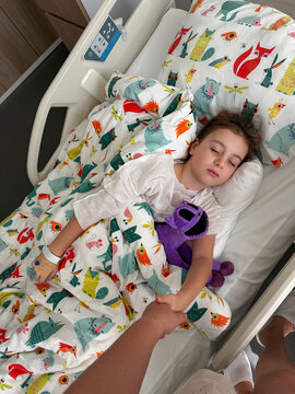 Child asleep in hospital bed after general anesthesia