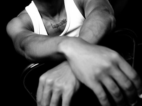Muscular man displaying chest tattoo with word impossible
